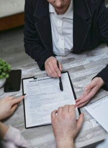 Roommates review a renters insurance policy beside household belongings at a shared kitchen table.