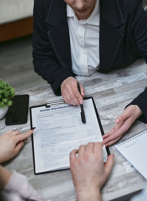 Roommates review a renters insurance policy beside household belongings at a shared kitchen table.